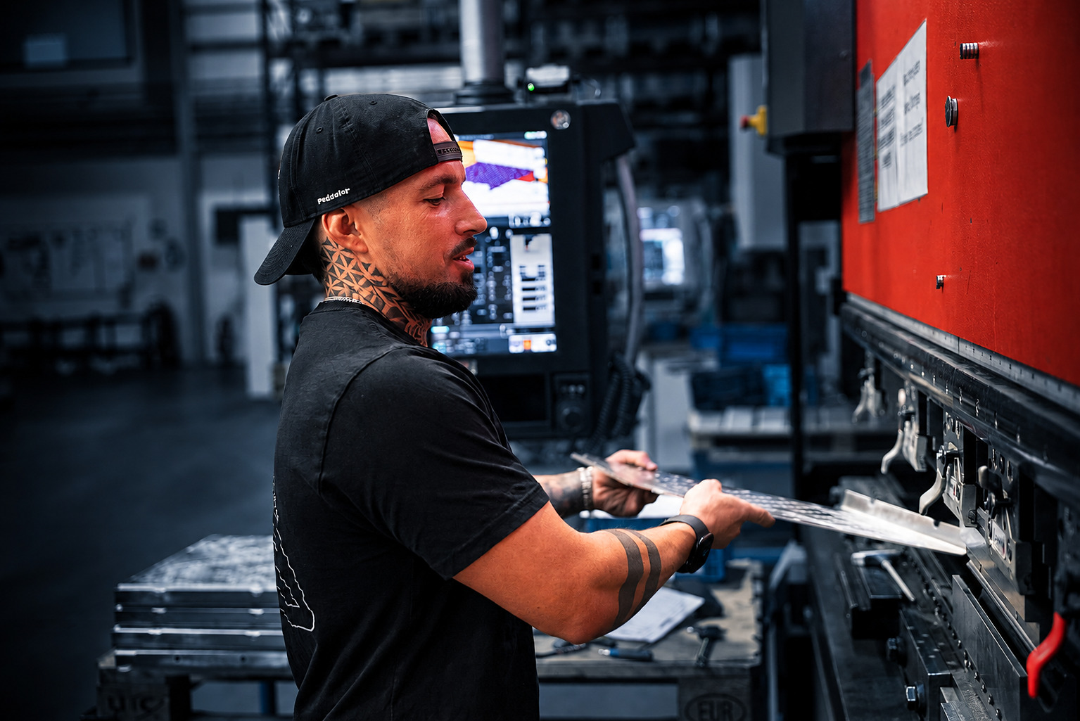 Mitarbeiter bearbeitet ein Metallblech an einer Abkantpresse bei ACROSS Solutions in Metal
