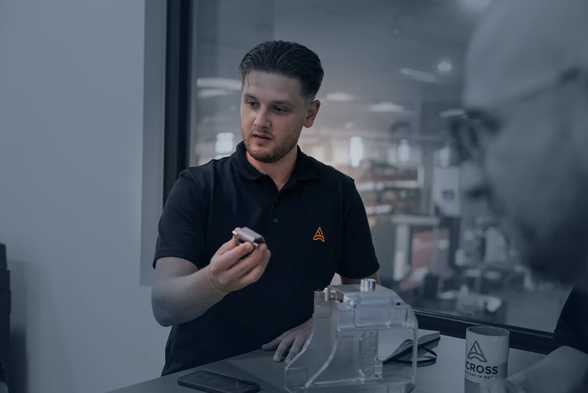 Mitarbeiter von ACROSS Solutions in Metal prüfen gemeinsam ein Metallbauteil.