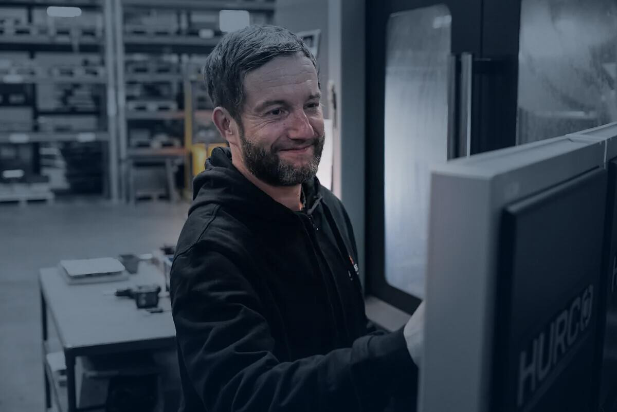 Mitarbeiter von ACROSS Solutions in Metal bei der Bedienung einer HURCO-Maschine.