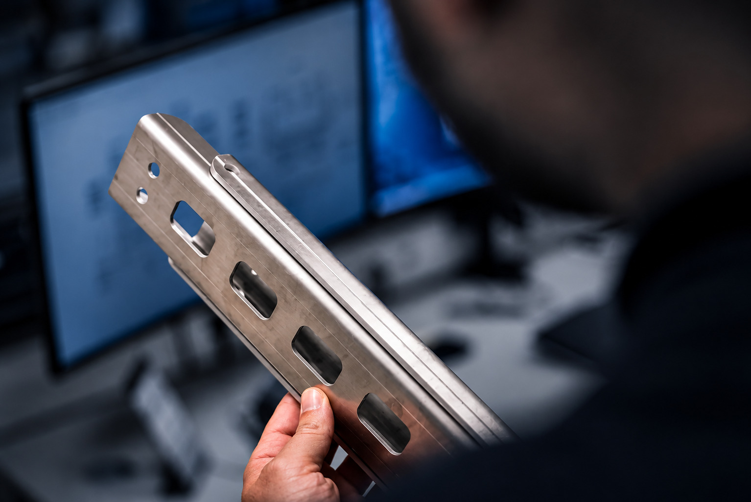 Mitarbeiter prüft ein präzise gefertigtes Metallbauteil bei ACROSS Solutions in Metal
