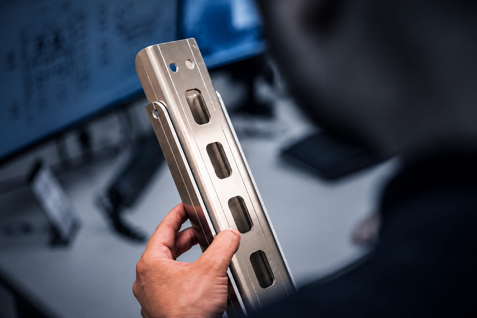Mitarbeiter prüft ein Metallbauteil bei ACROSS Solutions in Metal